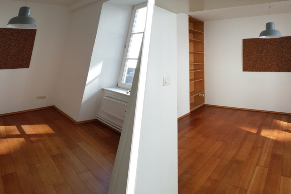 Der Vorherzustand meines Kundenprojekts kleines Zimmer als Büro einrichten, die Immobileinanzeige. Ein leerer Raum, Parkett, weiße Wände, Einbauregal, Kork-Pinnwand.