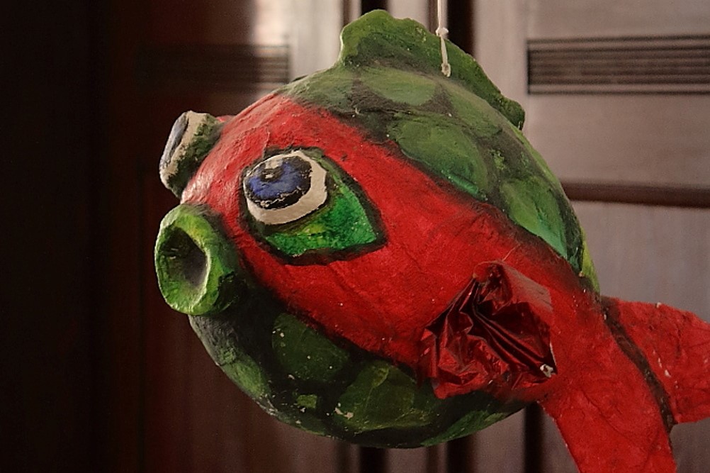 Ein Fisch aus Pappmaché, rot und grün mit Glubschaugen. Gebastelt für eine Kinder-Spieleecke.