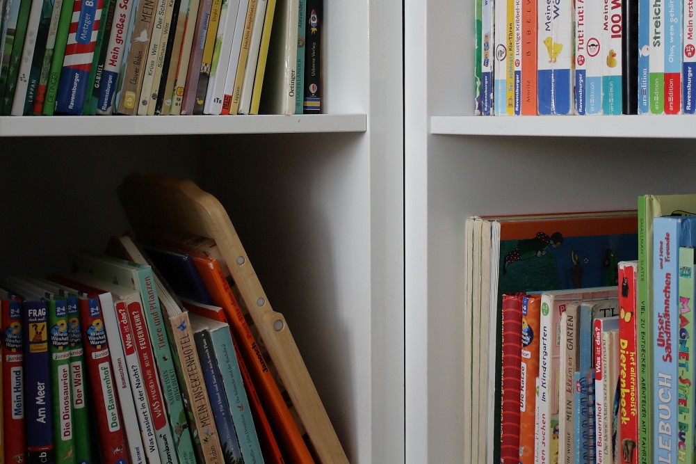 Wohnen auf kleinem Raum? Bibliothek mit bunten Kinderbüchern, angeordnet in Regalwürfeln.