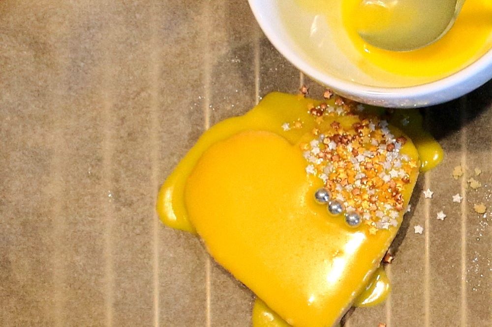 Ein Plätzchen in Herzform mit dickem gelben Zuckerguss als Platzhalter für den perfekten Zuckerguss.