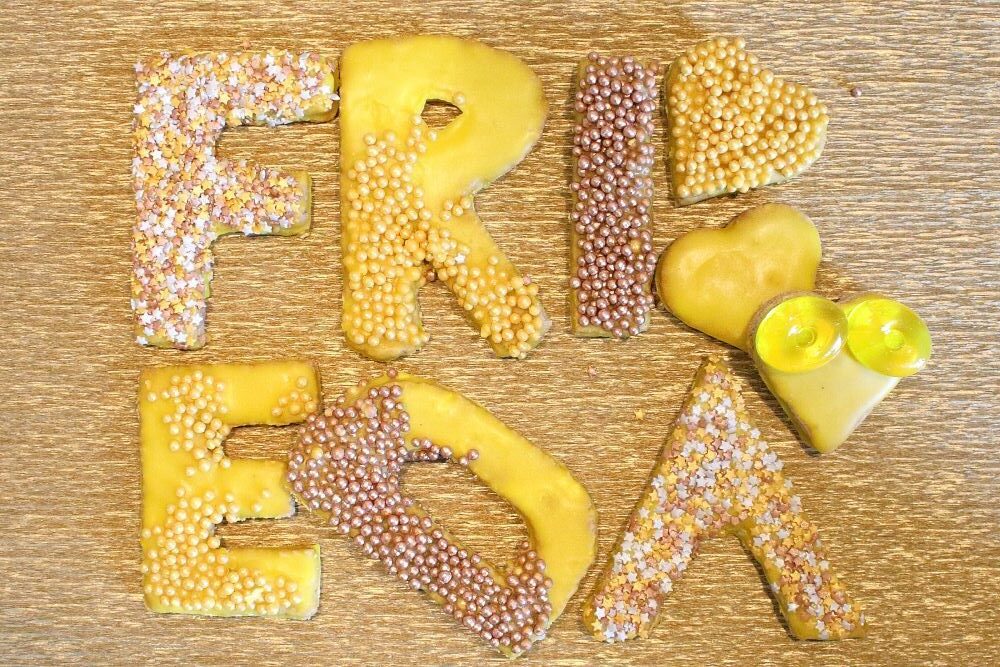 Plätzchen zur Schuleinführung, hier der Name Frieda. Mürbeteig-Buchstaben mit gelbem Zuckerguss und Verzierungen in bronze, silber, gelb. Und mit Gummitieren.