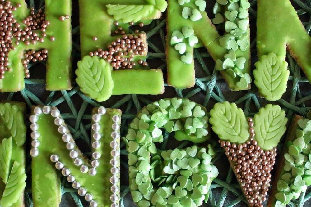 Mürbeteig-Buchstaben mit grünem Zuckerguss und Verzierungen in silber, bronze, grün.