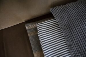Decken und Kissen auf einem Sofa. Material- und Mustermix.