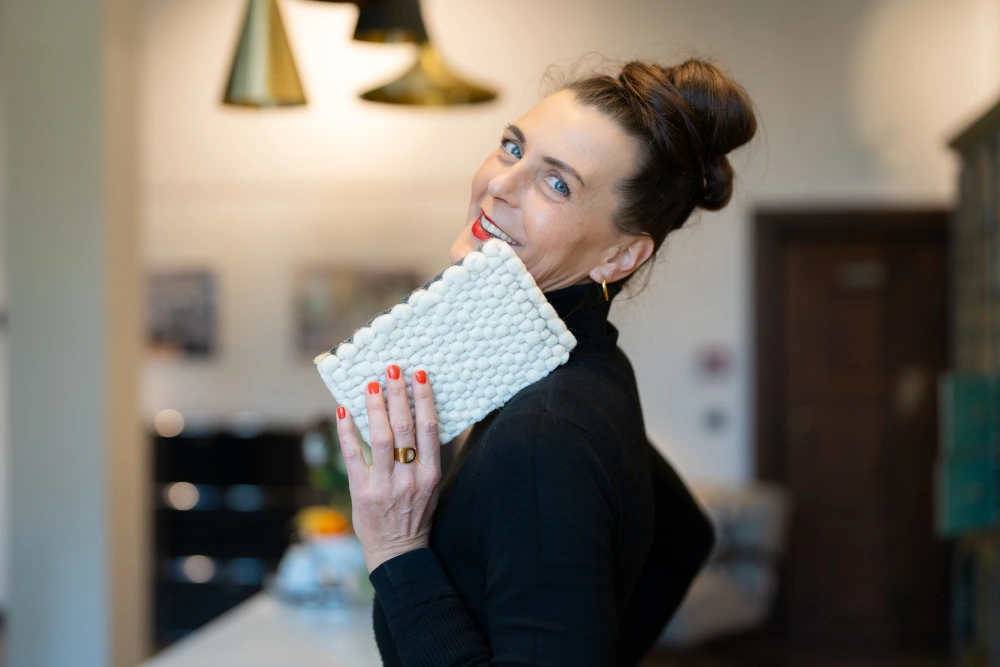 Eine Frau präsentiert ein Teppichmuster als Vorschlag für eine Wohnzimmereinrichtung.