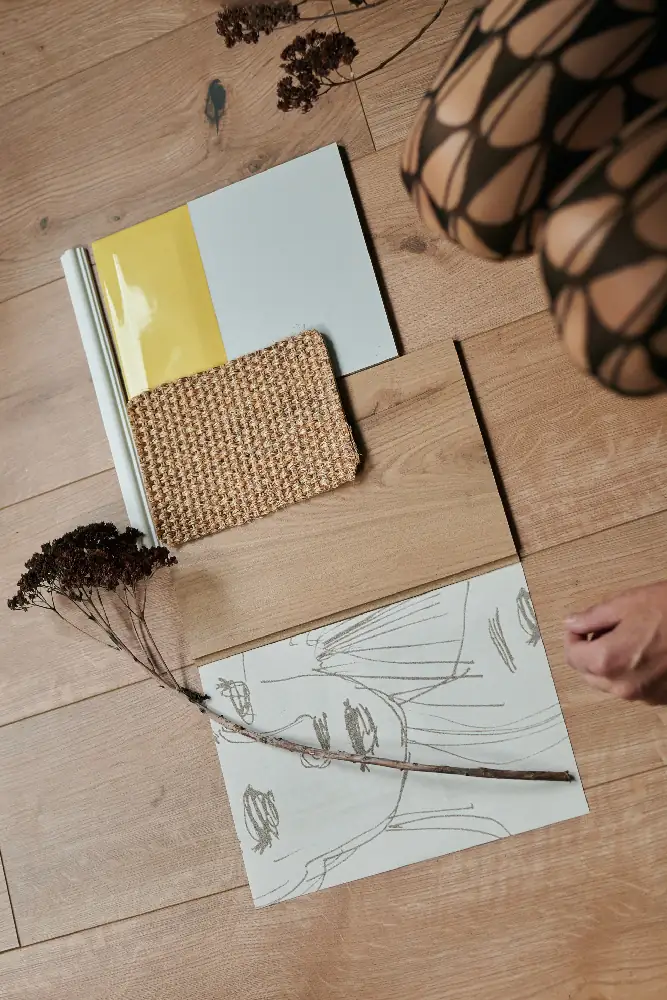 Farb- und Materialmuster mit Stoffprobe, Farbkarte und Skizze auf Holzboden angeordnet als Teil eines Interior Moodboards zur Innenraumgestaltung.